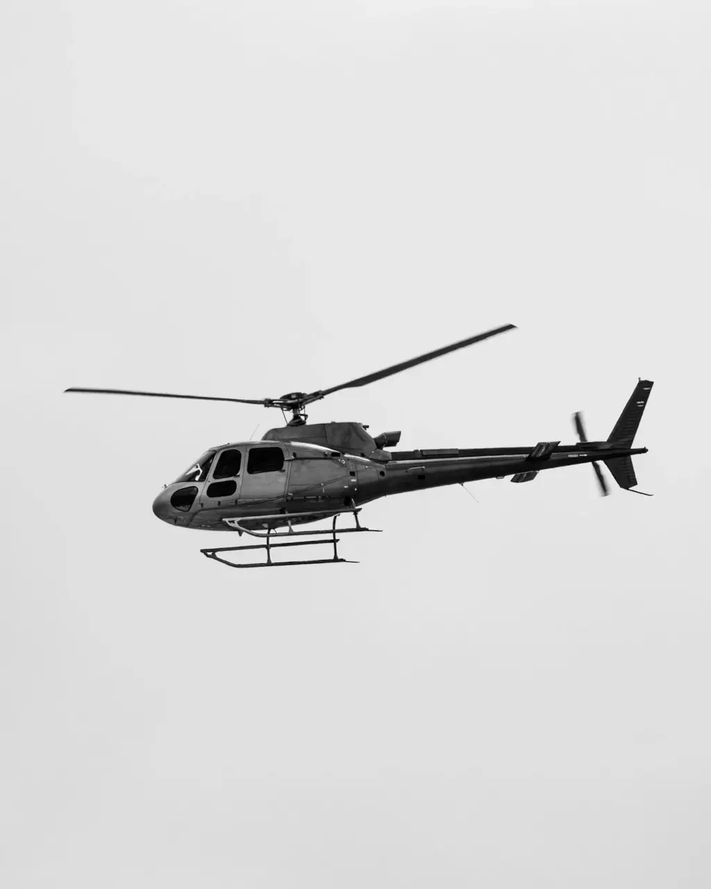 A helicopter in flight against a pale sky. Illustrative photograph.
