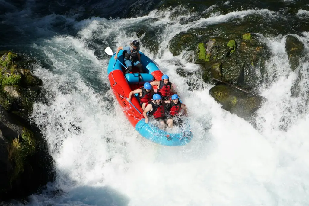 A raft of people in helmets running a white-water rapid. Illustrative photograph.